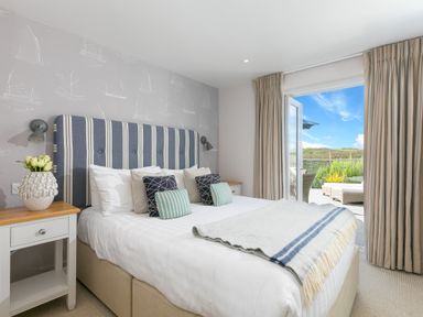 A bedroom with a striped headboard bedside tables and an open door leading to an outdoor patio at Verity Mullion