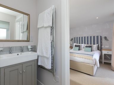 A bathroom with a sink and towels and a bedroom with a bed and nightstands at Verity in Mullion