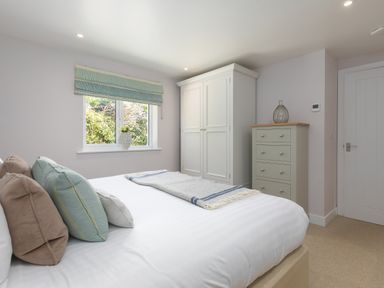 A bedroom with a bed with pillows a window white wardrobe and chest of drawers at Verity Mullion