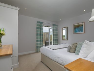 A bedroom with bed pillows curtains and wardrobe at Daphne in Mullion