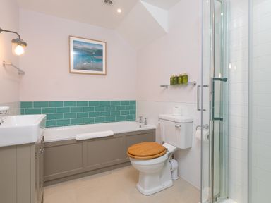 A bathroom with a bathtub sink toilet shower and framed picture at Daphne in Mullion