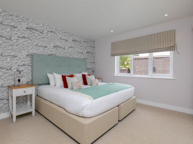 A bedroom with a bed and bedside tables and a window with a blind at Daphne in Mullion