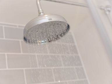 A close up of a shower head with water flowing in a bathroom at Daphne in Mullion