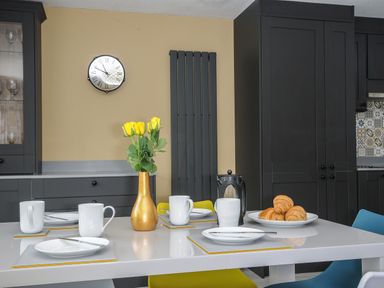 A kitchen dining table with white plates and mugs yellow roses in a vase and croissants in a plate at 37 Tamar in St Ann's Chapel near Callington