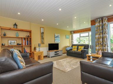 A living room with a sofa and bookshelf at 37 Tamar in St Ann's Chapel near Callington