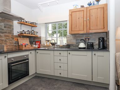 A kitchen with grey cabinets wooden wall cupboards oven kettle toaster and coffee machine at Hole Farm Stables in Bickington near Ashburton