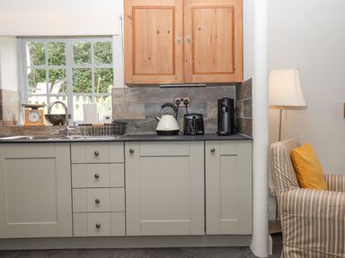 A kitchen counter with a sink kettle toaster coffee machine and wooden cabinets at Hole Farm Stables in Bickington near Ashburton