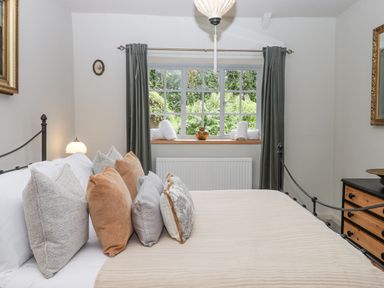 A bedroom with a bed and multiple pillows near a window with curtains at Hole Farm Stables Bickington near Ashburton