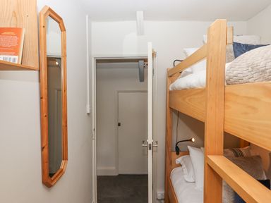 A small bedroom with wooden bunk beds a wall mirror and an open door to a hallway at Hole Farm Stables in Bickington near Ashburton