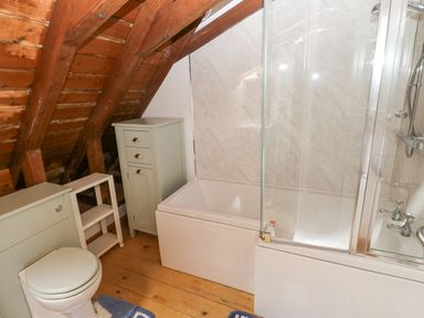 A bathroom with a toilet bathtub shower and wooden ceiling at Church Llygad Y Dyffryn Sarnau near Brynhoffnant
