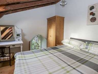 A bedroom with a bed, wardrobe, mirror and a stained glass window at Church Llygad Y Dyffryn Sarnau near Brynhoffnant