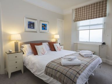 A bedroom with a bed lamps bedside tables and a window at Leylands in Salcombe