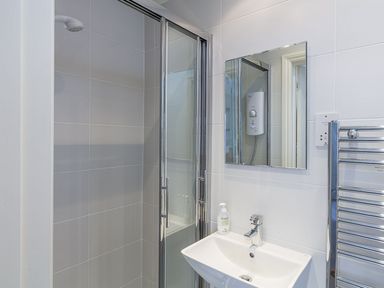 A bathroom with a shower area with sliding glass doors a sink with a faucet and a mirror above it at Leylands in Salcombe