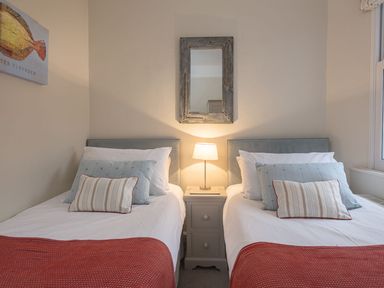A bedroom with two single beds a nightstand and a lamp at Leylands in Salcombe