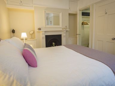 A bedroom with a bed a fireplace a mirror and a walk-in closet at Leylands in Salcombe