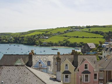 A view of rooftops overlooking a river with boats and green hills in the background at Leylands in Salcombe