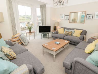 A living room with three gray sofas cushions a wooden coffee table and a television at Leylands in Salcombe
