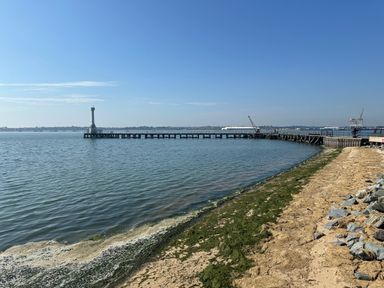 A shoreline with a pier extending into the water and a tower at the end of the pier at Inishnee House in Shotley Gate