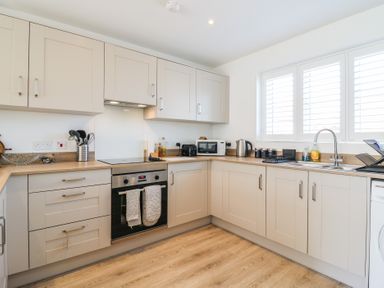 A kitchen with cabinets, sink, oven, microwave, and kettle at Inishnee House Shotley Gate