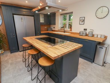 A kitchen with a central island with stools and a cooktop at The Grove in Wolfsdale near Haverfordwest