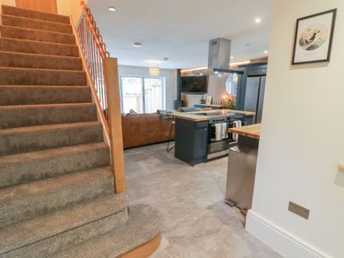 A carpeted staircase next to a kitchen and living area with a stove and sofa at The Grove in Wolfsdale near Haverfordwest