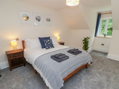 A bedroom with a double bed bedside tables and a window with blue curtains at The Grove in Wolfsdale near Haverfordwest