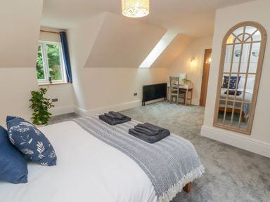 A bedroom with a bed pillows folded towels a desk chair plant and a tall mirror at The Grove in Wolfsdale near Haverfordwest