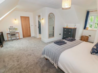 A bedroom with a bed a blanket a dresser a mirror a desk and a chair at The Grove in Wolfsdale near Haverfordwest
