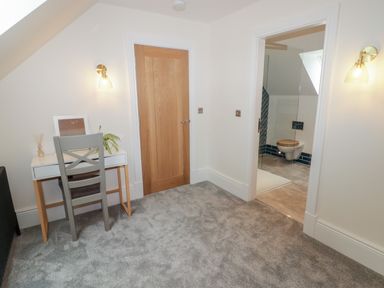 A small room with a desk and chair next to a wooden door and an open doorway showing a bathroom at The Grove in Wolfsdale near Haverfordwest