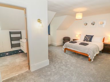 A bedroom with a double bed bedside tables lamps a chair and an ensuite bathroom at The Grove in Wolfsdale near Haverfordwest