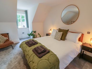A bedroom with a bed covered with white linens and green blankets at The Grove in Wolfsdale near Haverfordwest