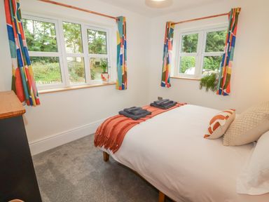 A bedroom with a bed with pillows and folded towels and colorful curtains at The Grove in Wolfsdale near Haverfordwest
