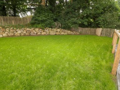 A fenced garden area with green grass rocks and trees at The Grove in Wolfsdale near Haverfordwest