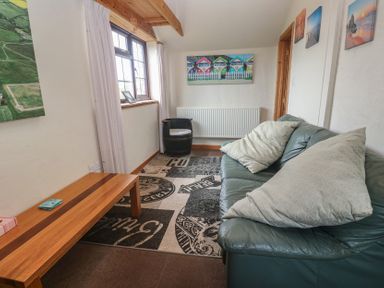 A snug area with a sofa and coffee table at Horseshoe Cottage Near Holywell Bay