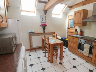 A kitchen with a table and chairs at Horseshoe Cottage Near Holywell Bay