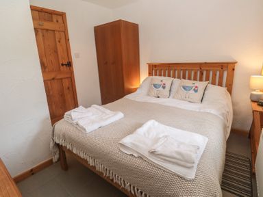 A bedroom with a bed and bedside table at Horseshoe Cottage Near Holywell Bay