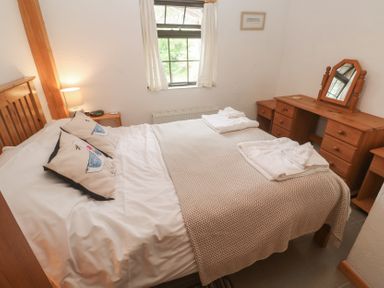 A bedroom with a double bed and dresser at Horseshoe Cottage near Holywell Bay