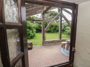 A view of a garden with a table and chairs at Horseshoe Cottage near Holywell Bay