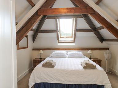A bedroom with a bed under a skylight window and wooden beams at Ixworth Cottage in Little Woodford near Ottery St Mary