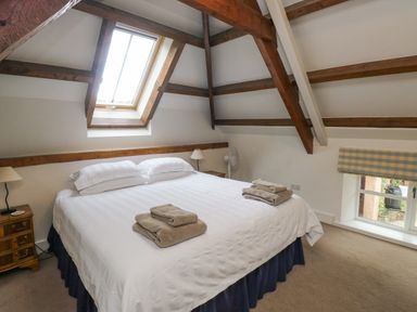 A bedroom with a large bed under a skylight and exposed wooden beams at Ixworth Cottage Little Woodford near Ottery St Mary