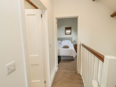 A hallway leading to a bedroom with a bed and bedside table at Ixworth Cottage in Little Woodford near Ottery St Mary