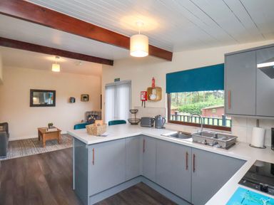 A kitchen with grey cabinets and a white countertop connected to a living room with a coffee table at Ramson in Saltburn-By-The-Sea