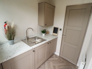 A kitchen corner with a sink plant cabinets and a door at Sunset Lodge in Woodhall Spa
