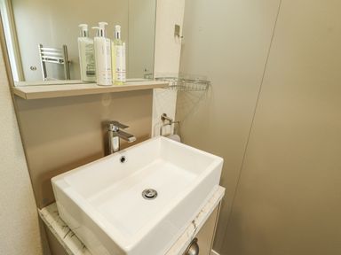 A bathroom sink with a faucet soap dispensers a mirror and a towel ring at Sunset Lodge in Woodhall Spa