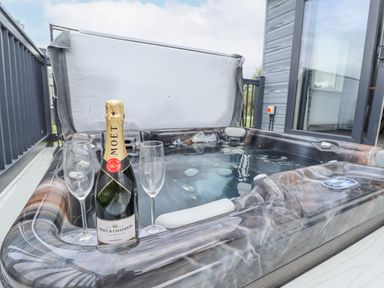 An outdoor hot tub with a bottle of Moet champagne and two empty champagne glasses at Sunset Lodge in Woodhall Spa