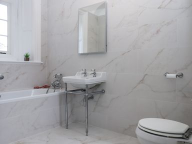 A bathroom with a bathtub, sink, toilet, and mirror at Alston Hall Battisborough Cross