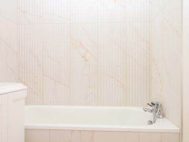 A bathroom featuring a bathtub and wall tiles at Alston Hall near Mothecombe Beach