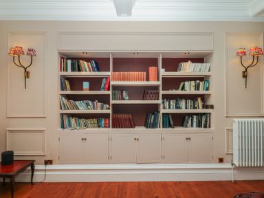 A bookshelf with books and a radiator at Alston Hall near Mothecombe Beach