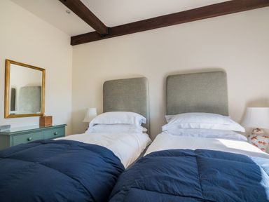A bedroom with two single beds with blue comforters and gray headboards a green dresser with mirror and two bedside lamps at Bank Barn Wreay Watermillock