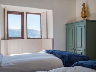 A bedroom with two beds next to a window and a cabinet with a statue on top at Bank Barn Wreay in Watermillock